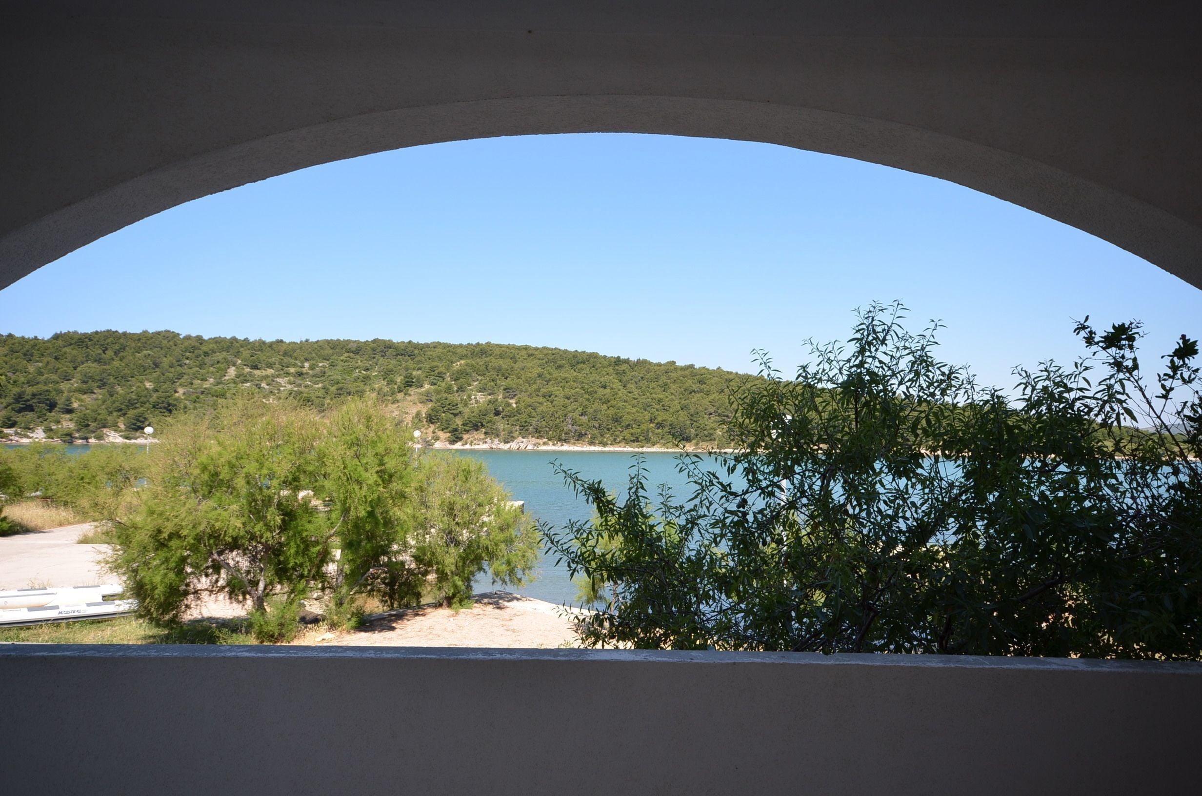A view through an archway of a lake, surrounded by greenery and hills.