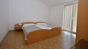 A bedroom with a wooden bed, a nightstand, and a window with blinds. - Apartments Zlatko (Jadrtovac)