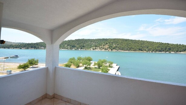 A balcony with a view of a lake and a forested hill. - Apartments Zlatko (Jadrtovac)