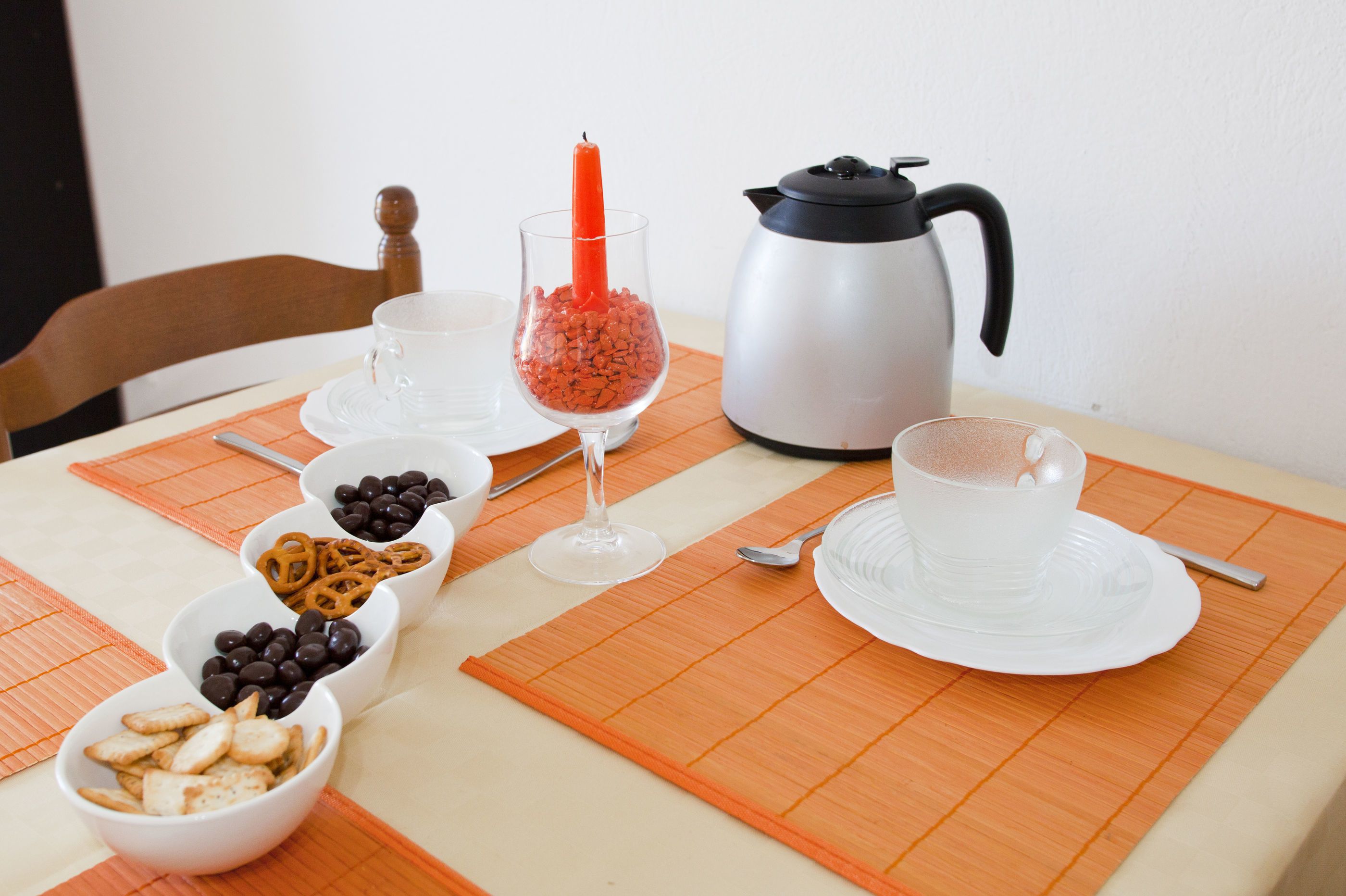 Una mesa servida con diferentes aperitivos, una copa de vino tinto, una cafetera y una taza de café.