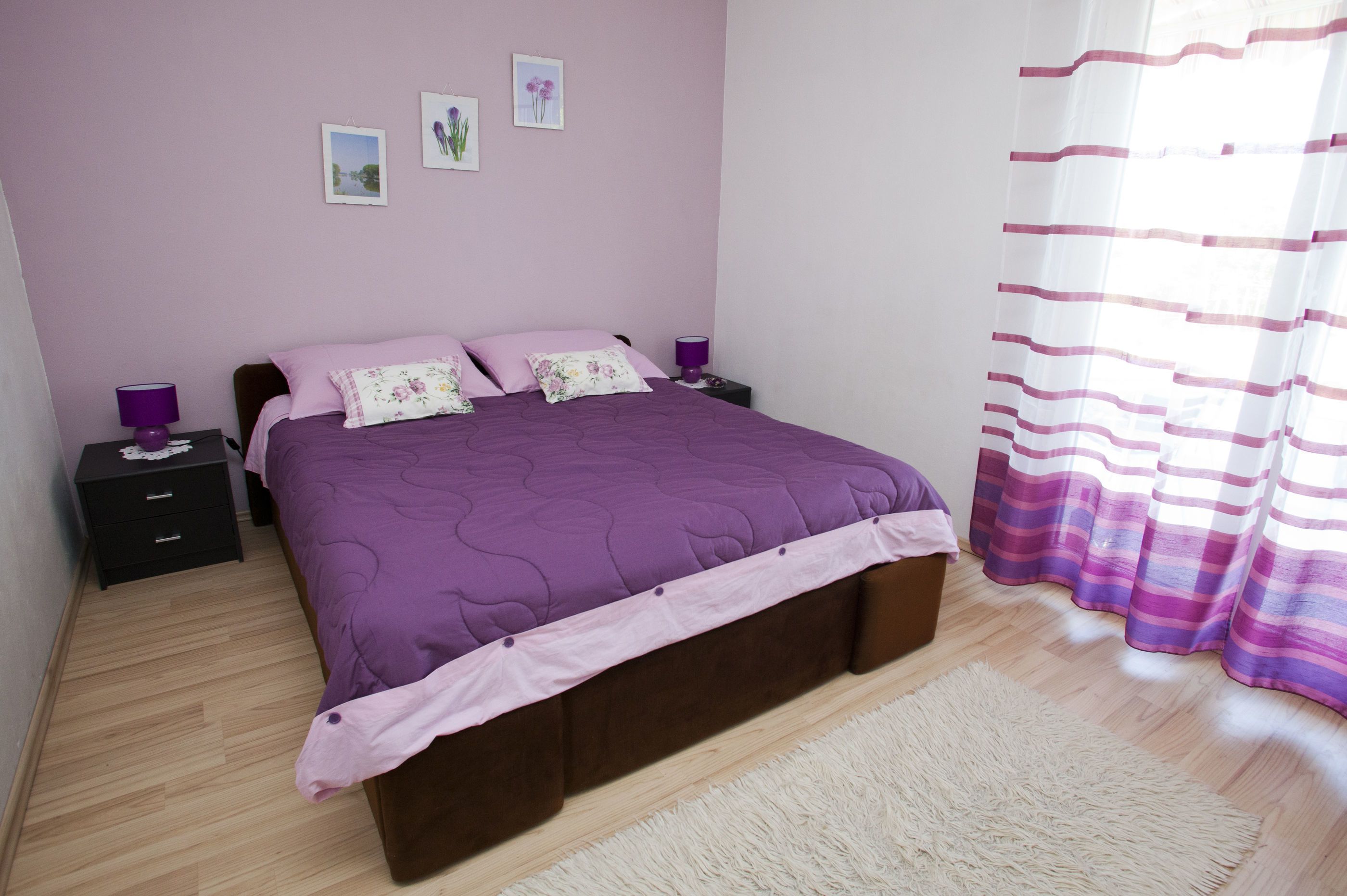 A bedroom with a bed, nightstands, a rug, and curtains.