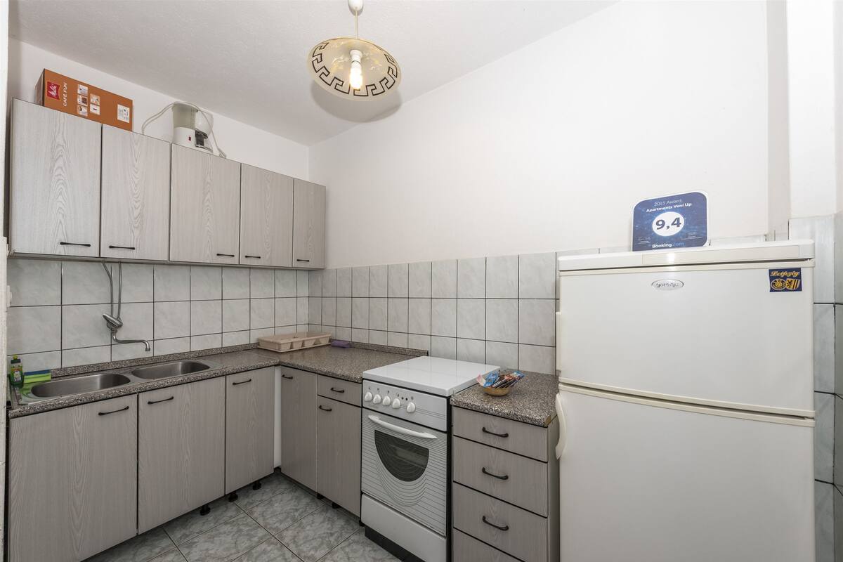 A kitchen with light wood cabinets, a white refrigerator, and a built-in oven.