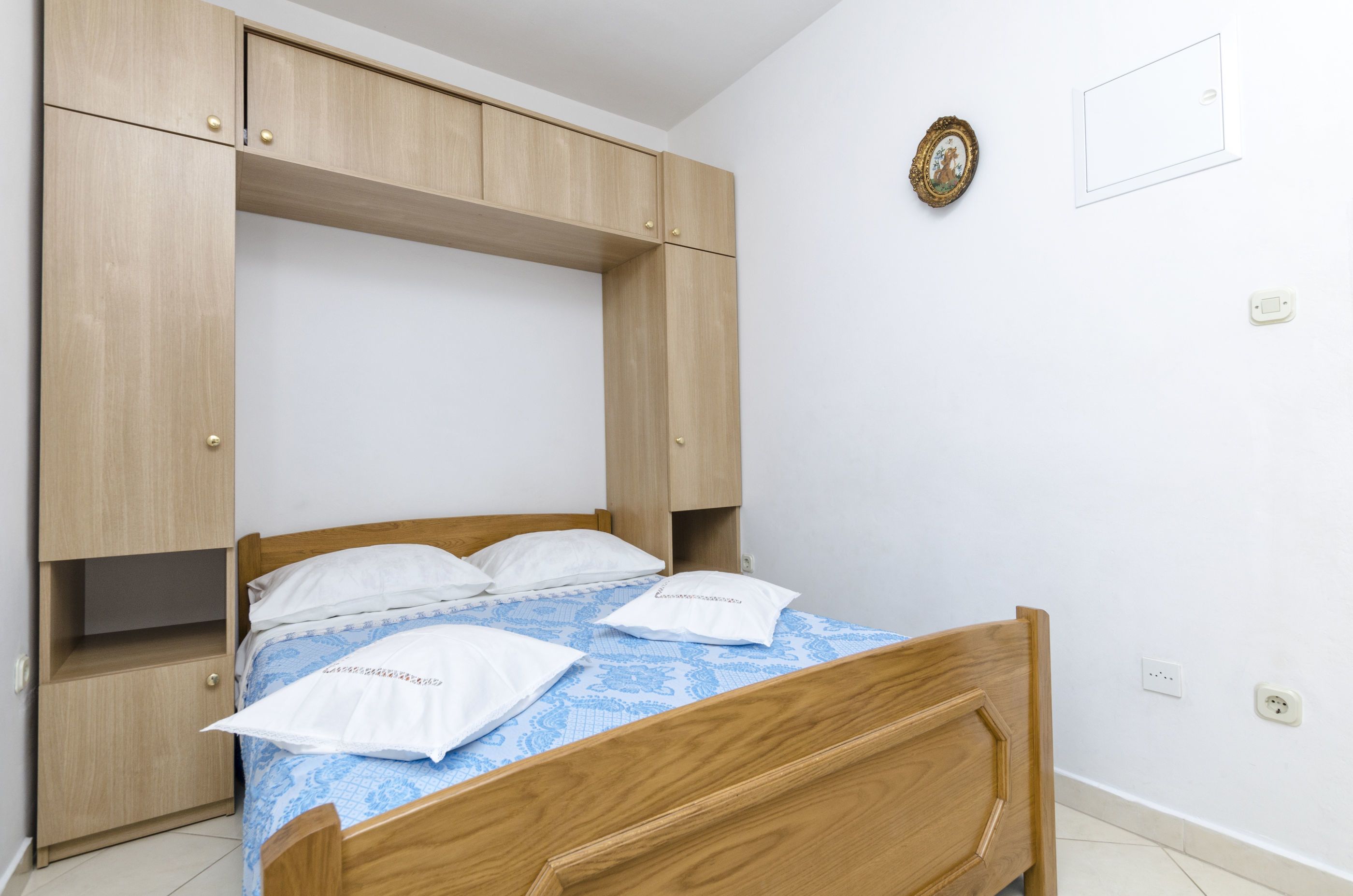 A bedroom with a wooden bed, a built-in wardrobe, and a wall-mounted clock.