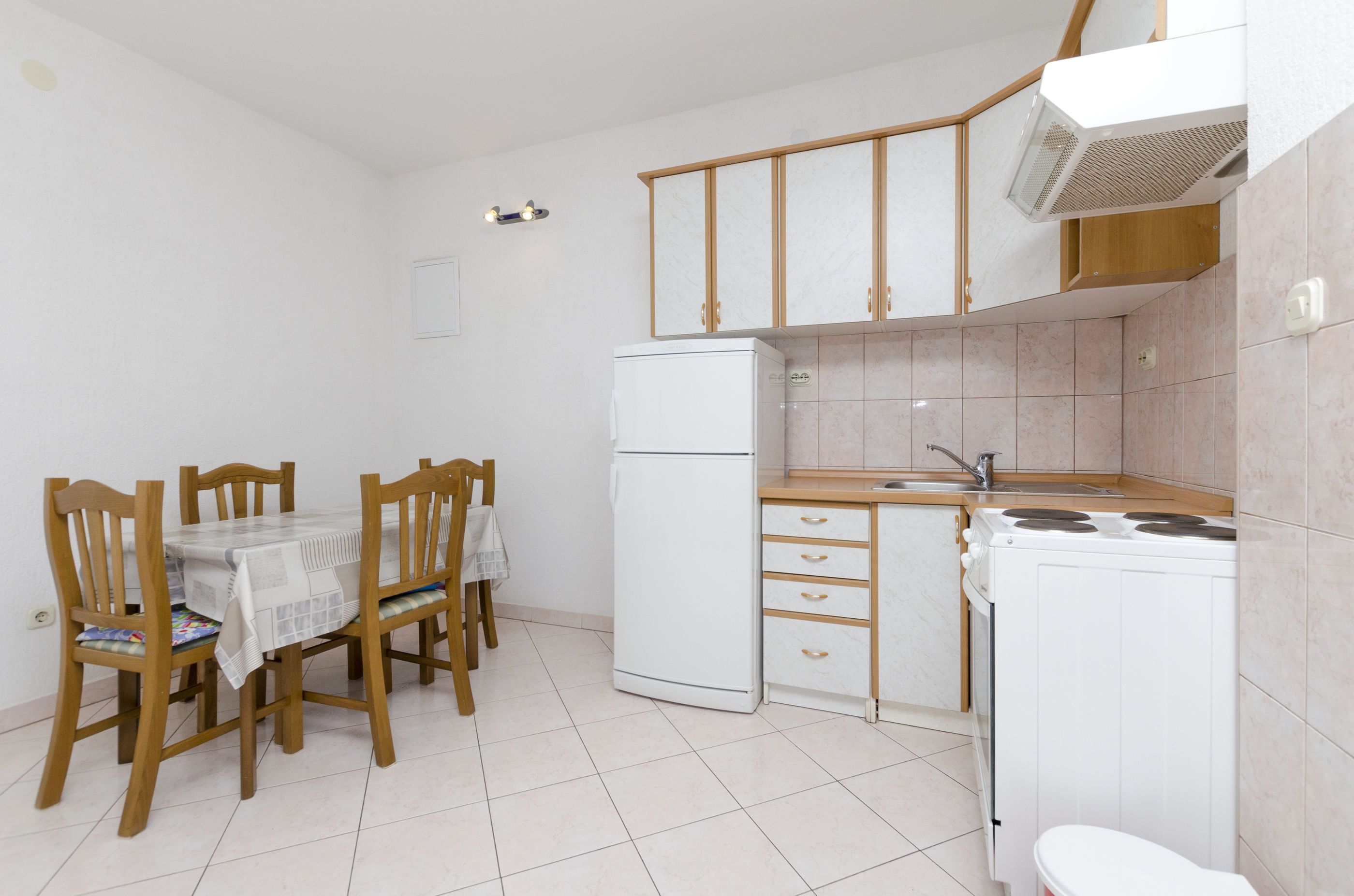 A compact kitchen with a dining table, chairs, a refrigerator, a stove, and a sink.
