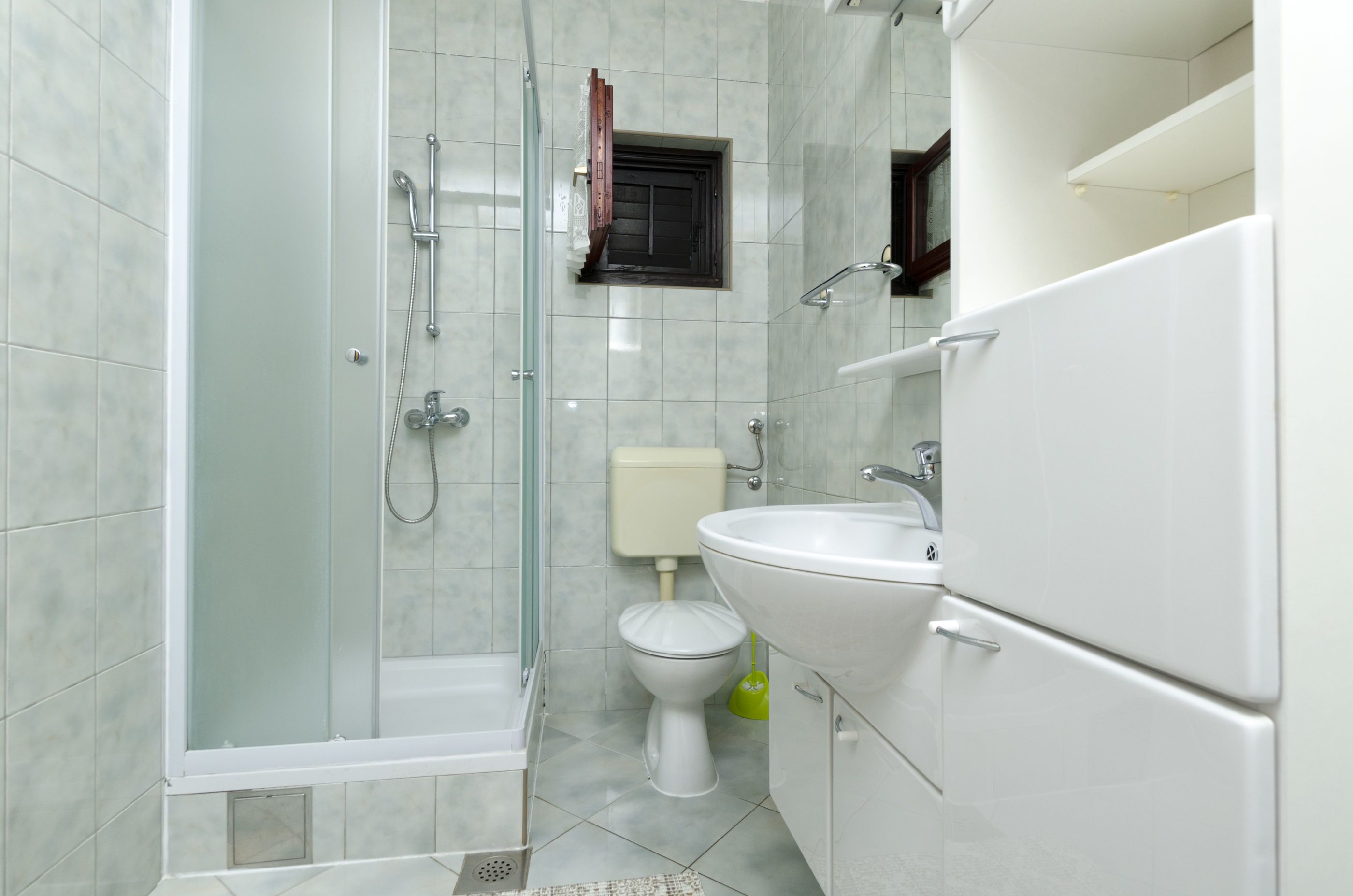 A modern bathroom with a glass-enclosed shower, a toilet, and a sink.