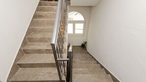 Eine Treppe mit Metallgeländer und beigefarbenen Fliesen.