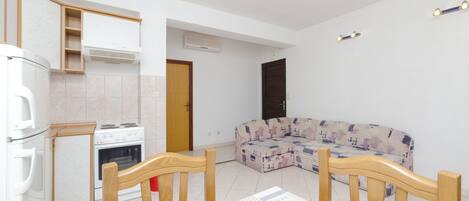 A compact living space with a kitchenette, a sofa, and a dining table.