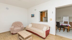 Ein Wohnzimmer mit einer Couch, einem Sessel, einem Holztisch und einem Essbereich mit Tisch und Stühlen.