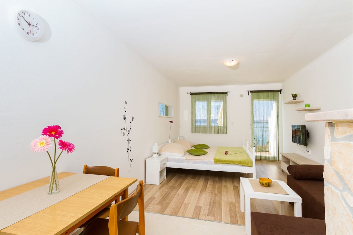 A compact living space with a bed, a dining table, and a sofa.