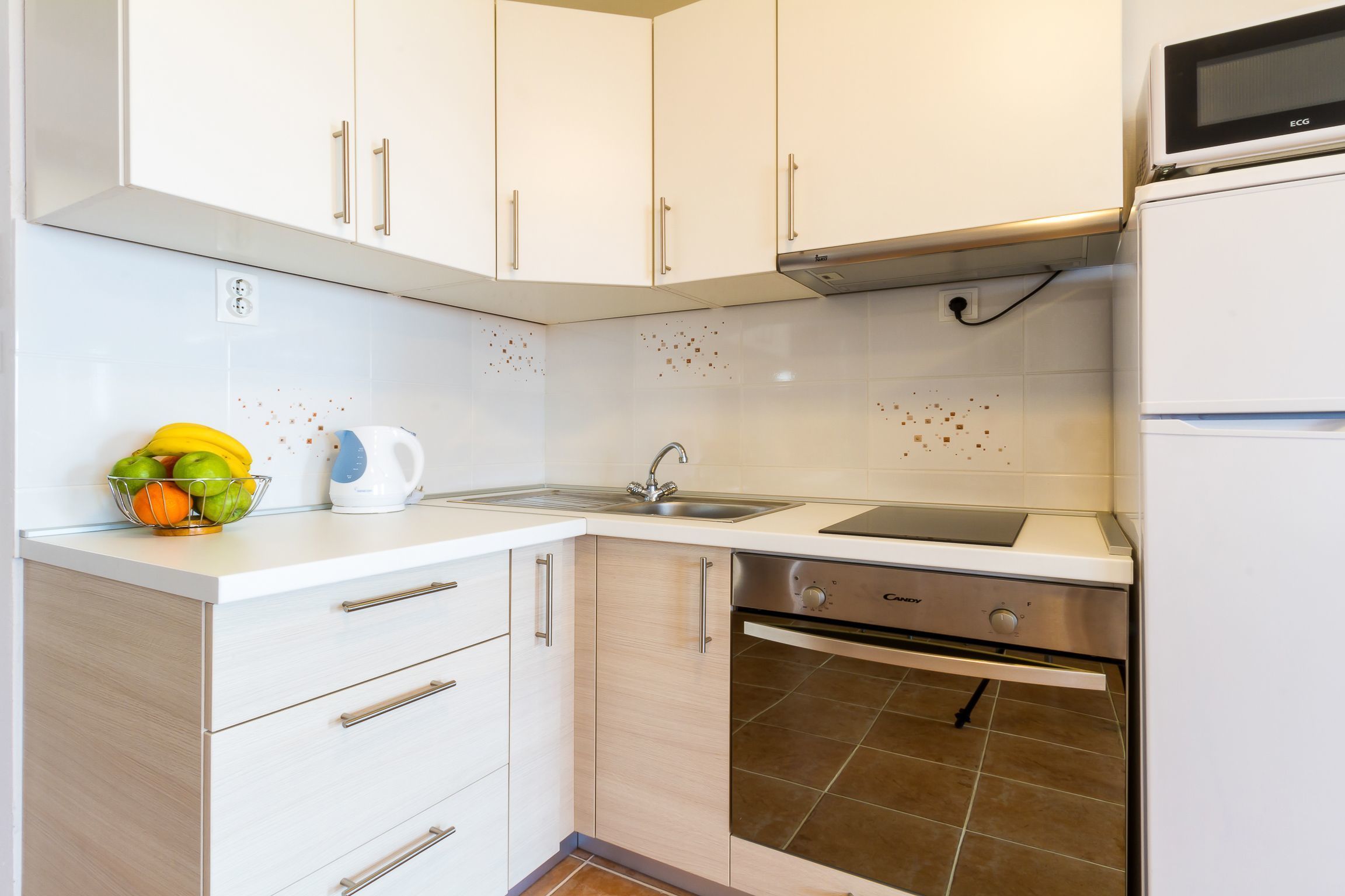 A modern kitchen with white cabinets, a stainless steel dishwasher, and a microwave.