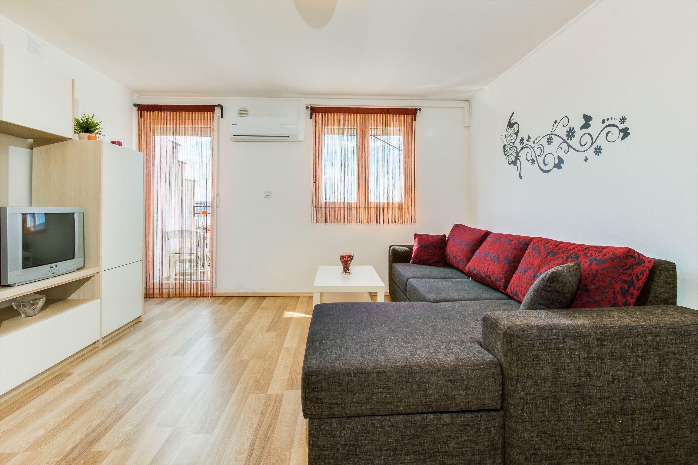 A modern living room with a sofa, a small table, and a television.