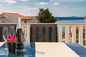 Ein Balkon mit Esstisch, mit Blick auf ein Gewässer und Häuser.