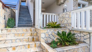 A stone staircase leading to a porch with white railings and a small garden area. - Apartments Bregovec Maslenica (Maslenica)