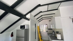 Una cocina moderna con armarios blancos, un refrigerador de acero inoxidable, un microondas y una escalera amarilla.