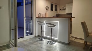 Una cocina moderna con barra, que incluye un taburete alto y una lámpara colgante.