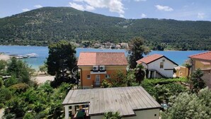 Un pueblo costero con edificaciones que dan al lago, rodeado de vegetación y colinas.