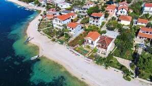 Luchtbeeld van een kustgebied met huizen, een strand en boten.