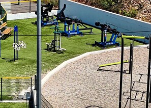 Outdoor exercise equipment, a paved area, and a metal fence. - Apartments Nediljka (Dolac)