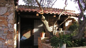 Un edificio de piedra con techo de tejas, entrada de piedra y plantas en macetas.