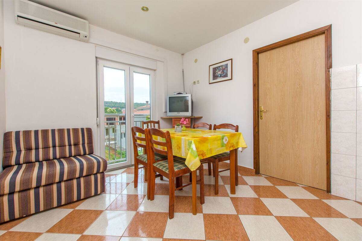 Un coin repas avec une table dressée pour quatre personnes, un canapé, un téléviseur et une porte.