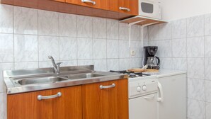 Eine kleine Küche mit Spüle aus Edelstahl, Holzschränken, einer Mikrowelle und einer Kaffeemaschine.