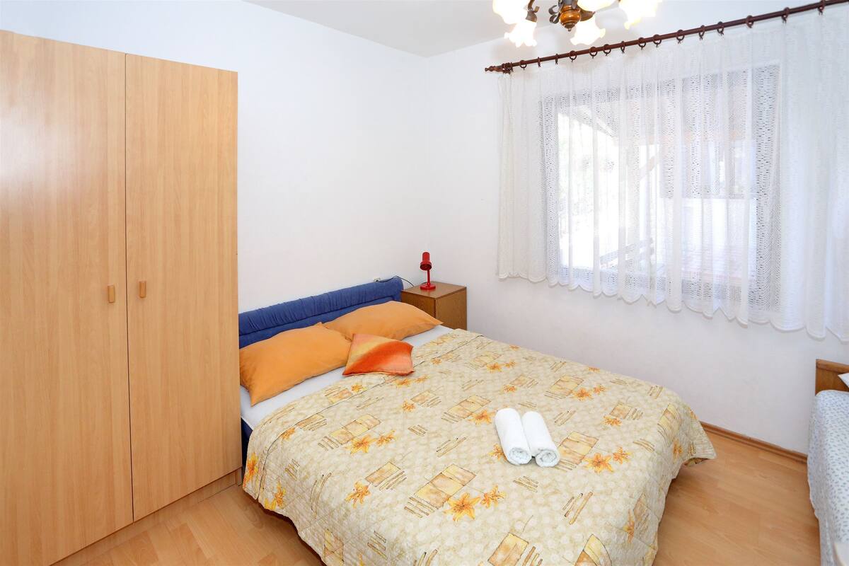 Une chambre à coucher comprenant un lit, une armoire, une table de chevet et une fenêtre avec des rideaux.