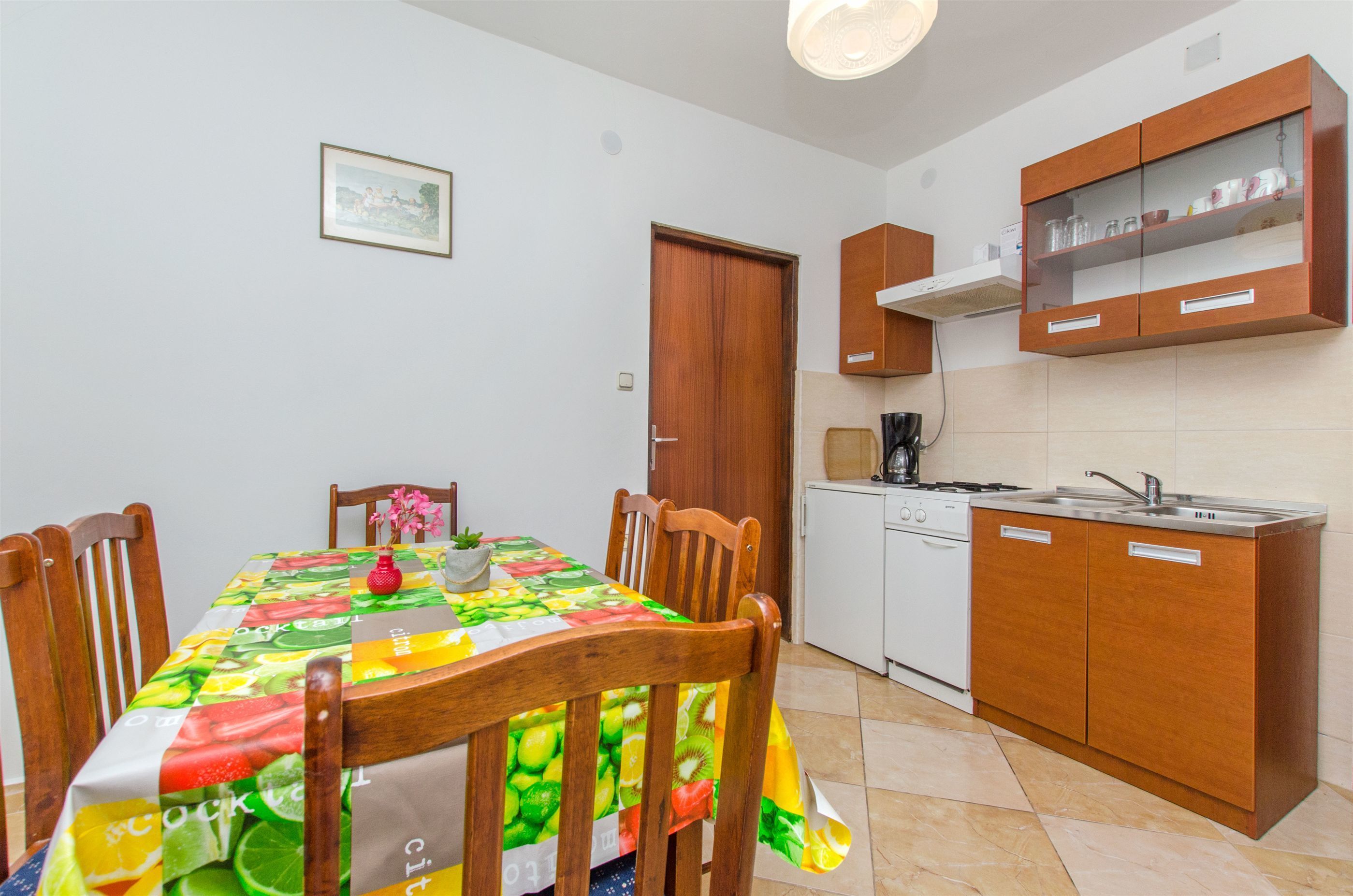 A compact kitchen with wooden cabinets, a white stove, and a tiled backsplash.