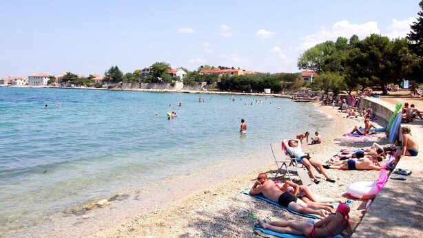 Ein Strand mit Personen, die sich sonnen und schwimmen.