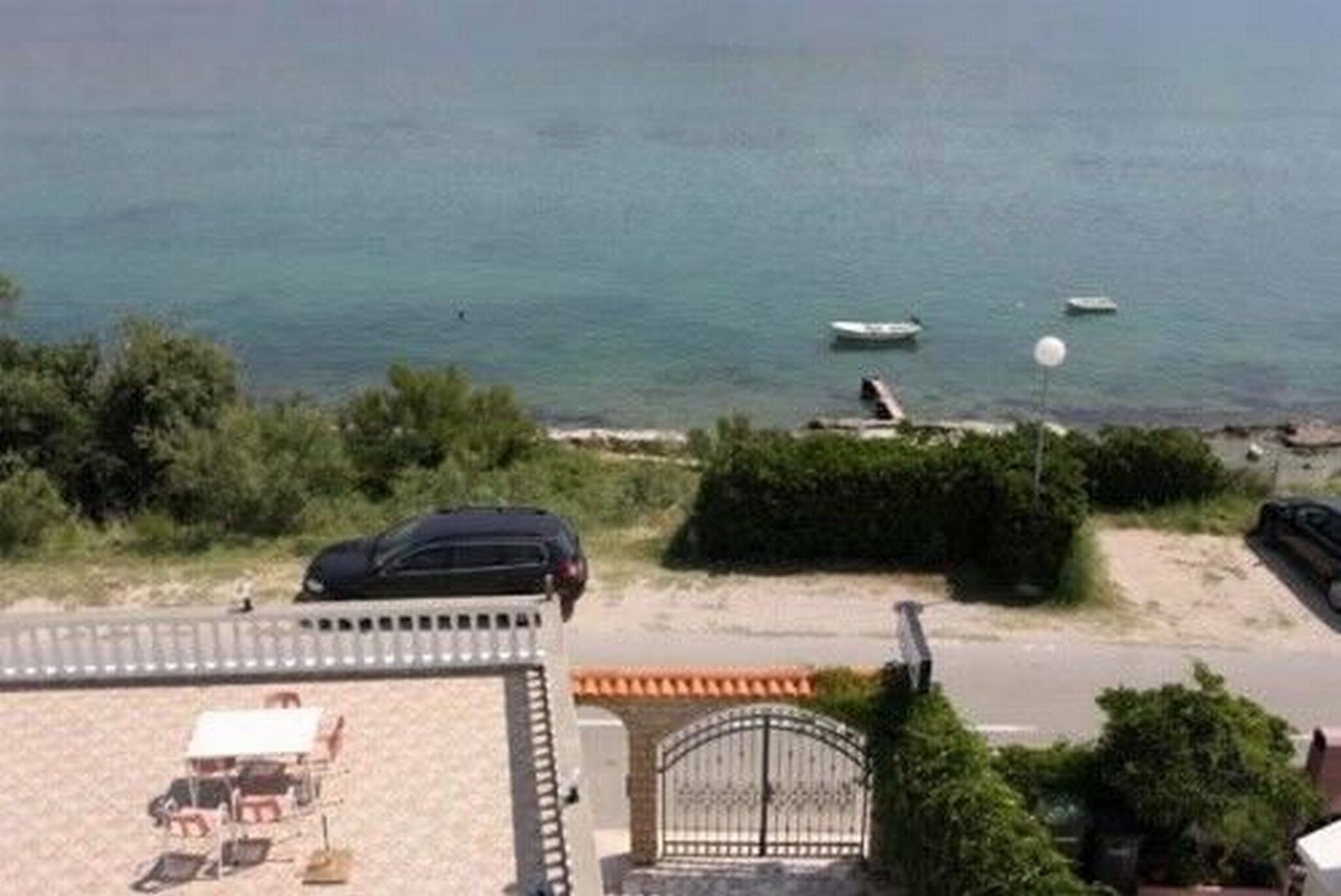 A coastal view with a beach, a gate, and a parked car.