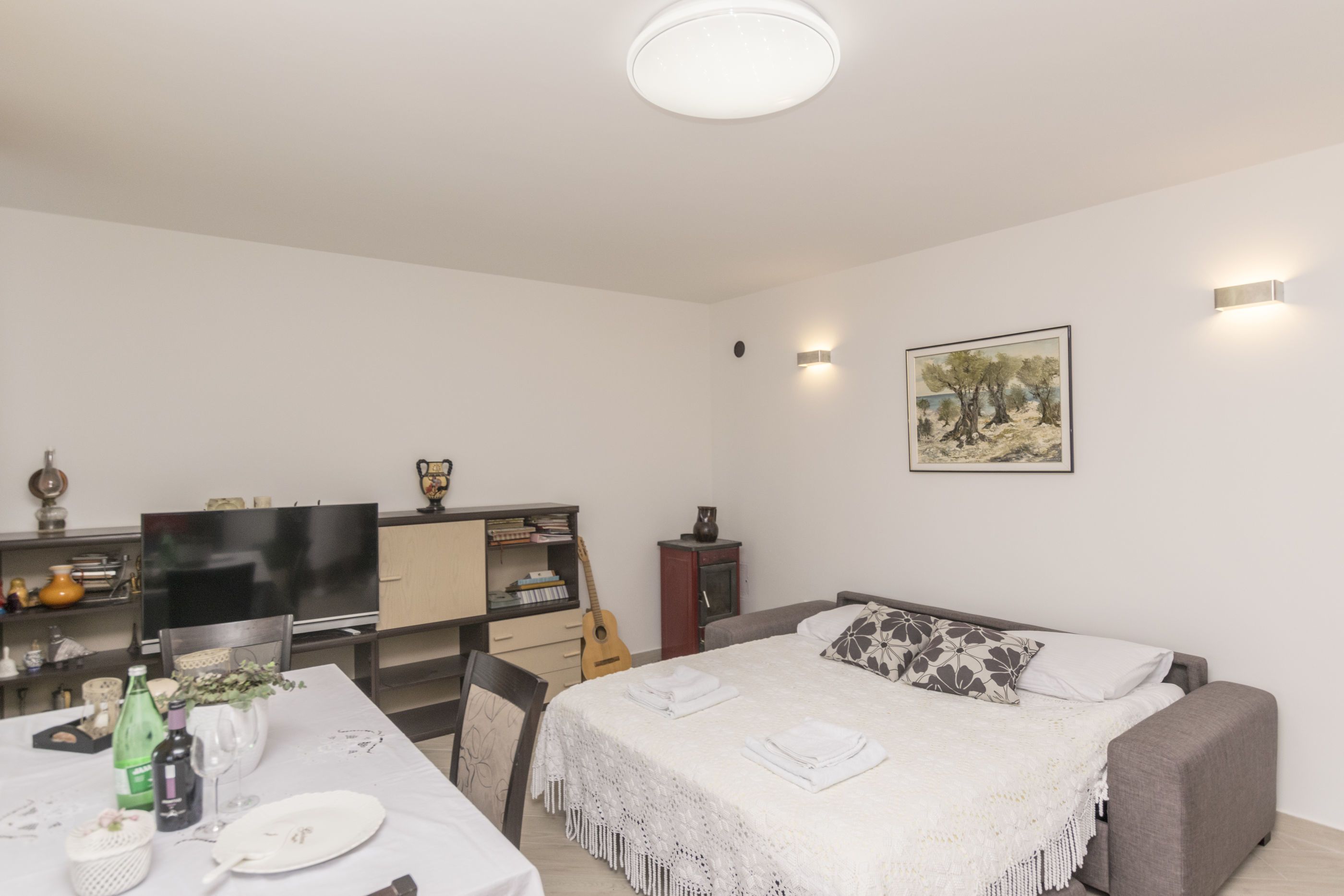 A bedroom with a bed, a TV, a desk with a chair, and a bookshelf.