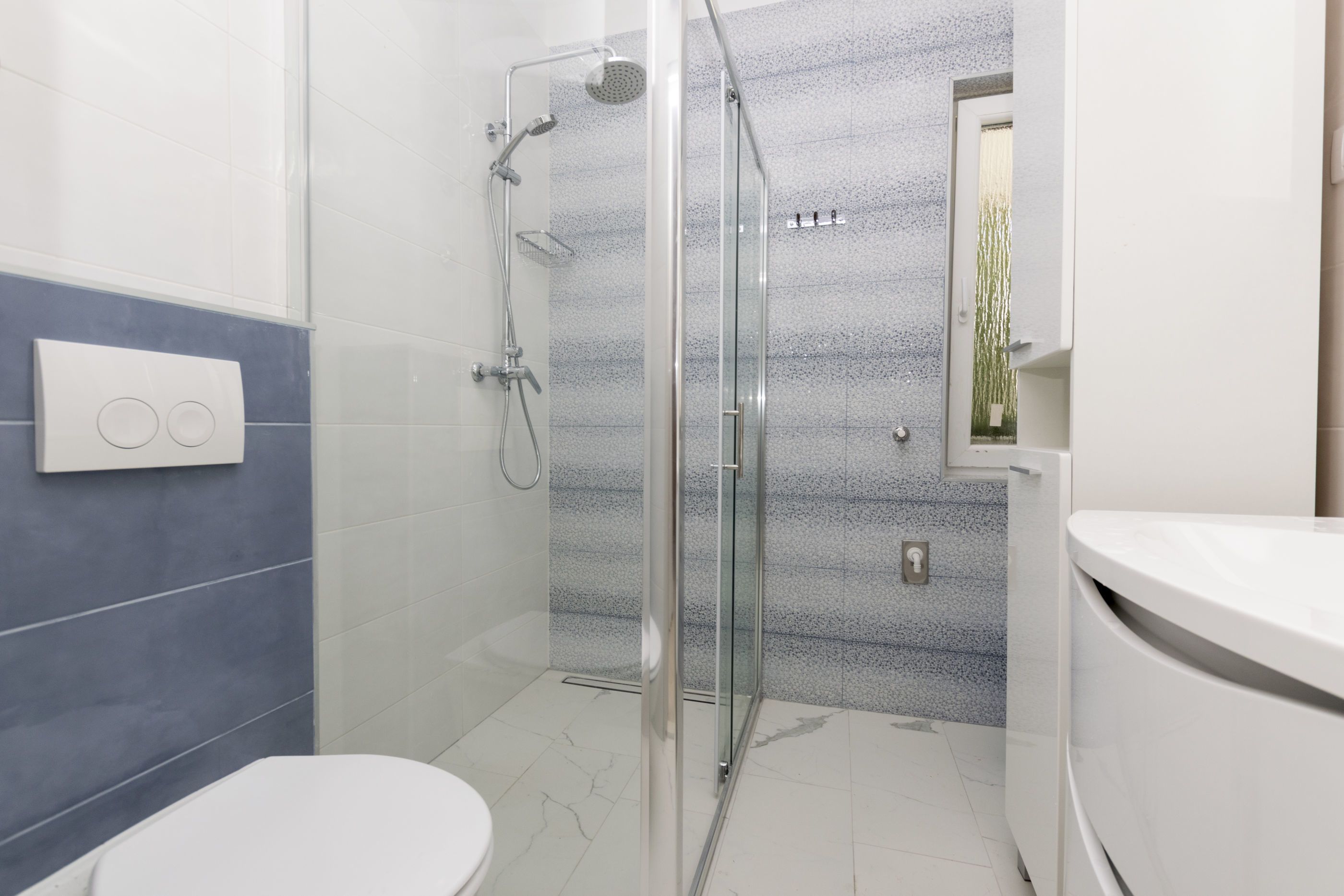 A modern bathroom with a glass-enclosed shower, a toilet, and a sink.