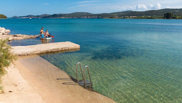 A clear lake with a sandy beach and a small dock. - Mobile Home Sea Turtle (Pasman)