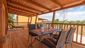 A wooden deck with a table and chairs, a potted plant, and a view of the landscape. - Mobile Home Sea Turtle (Pasman)
