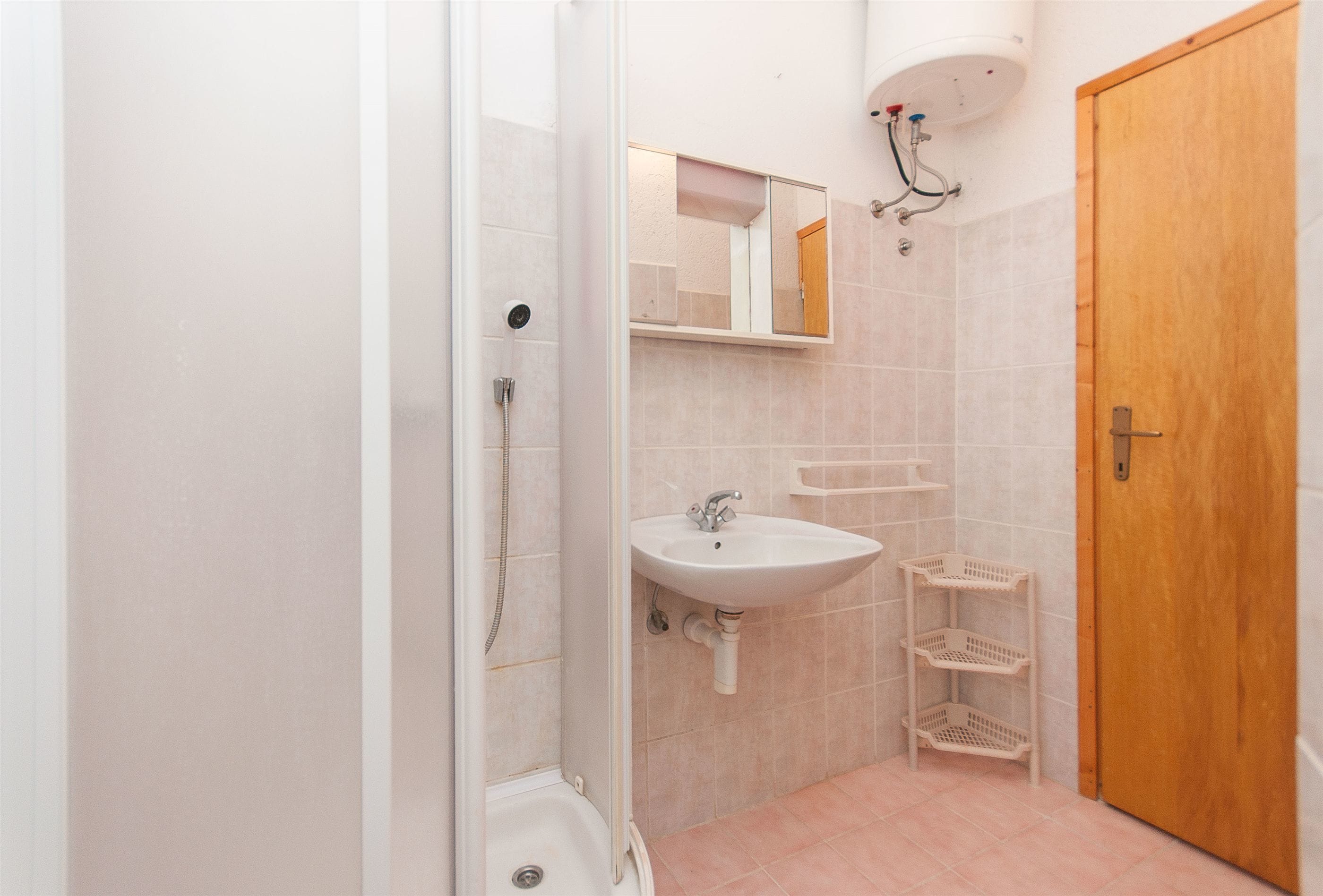 Une salle de bain avec une douche, un lavabo et une porte en bois.