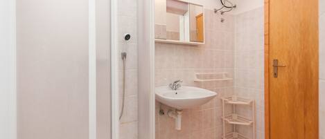 Une salle de bain avec une douche, un lavabo et une porte en bois.