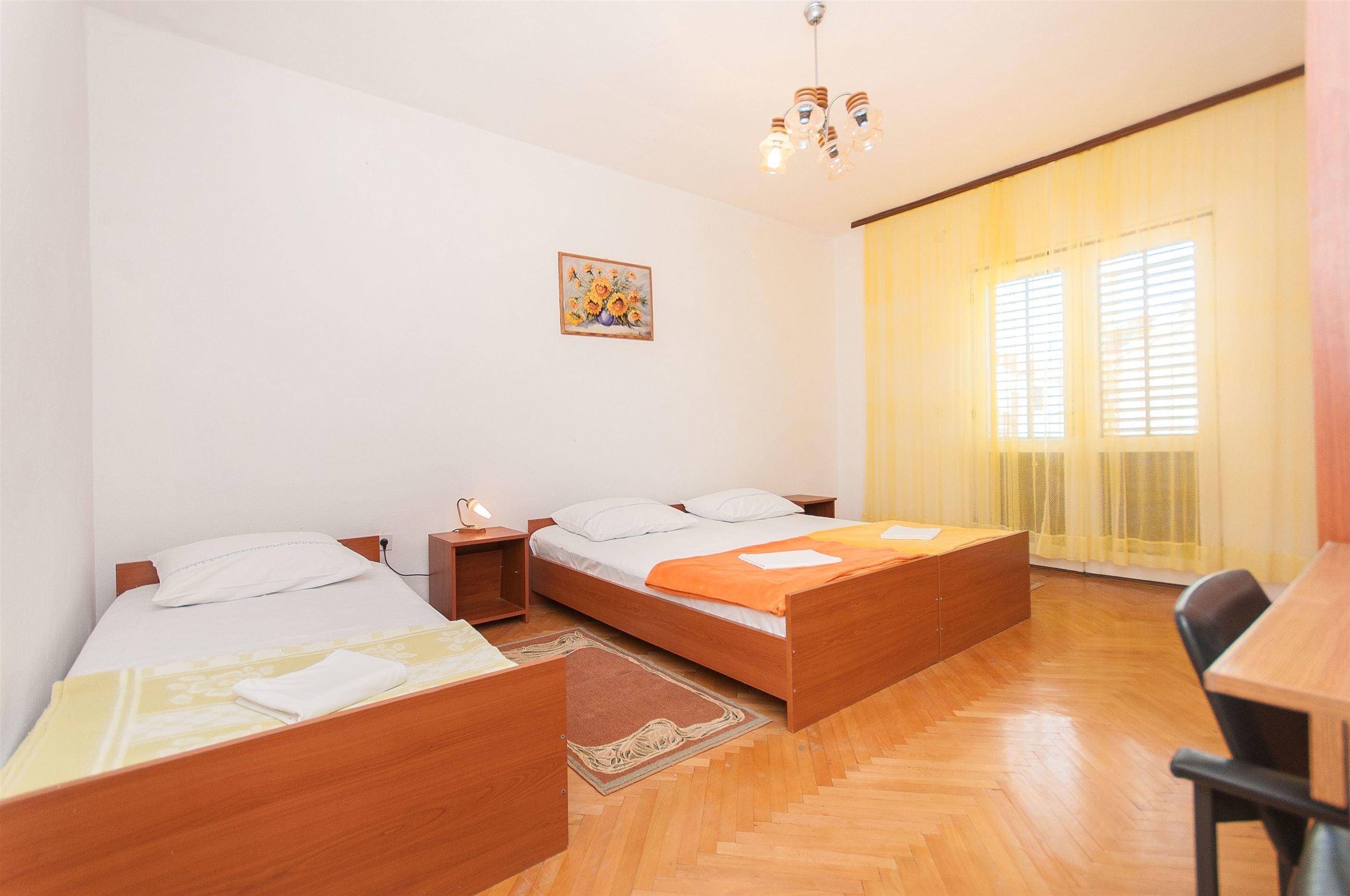 A bedroom with two wooden beds, a desk, and a chair.