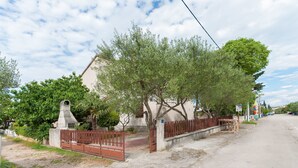 A residential street with a house, a metal gate, and a paved sidewalk. - Apartment Slavko (Biograd)