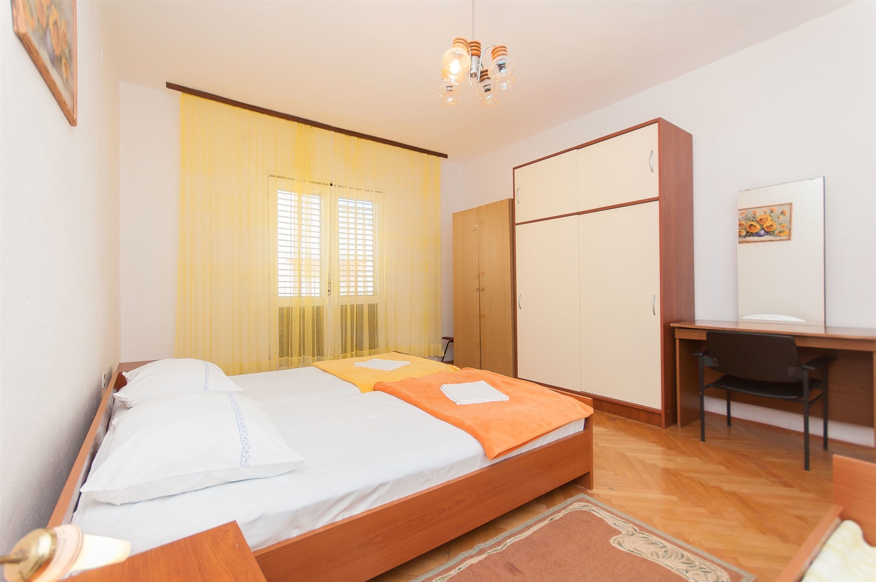 A bedroom with a bed, a desk, and a wardrobe.