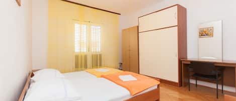A bedroom with a bed, a desk, and a wardrobe.