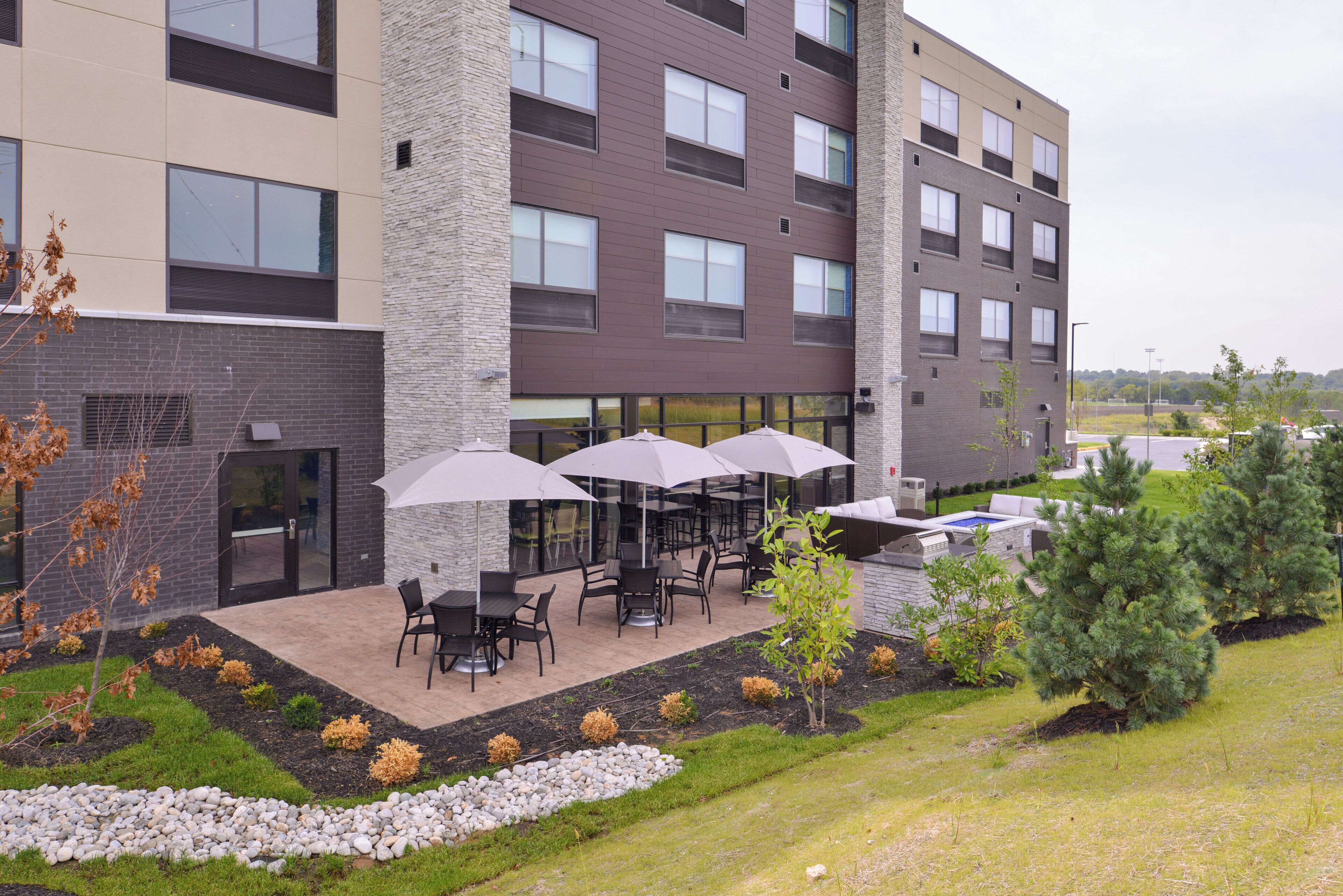 A modern building with a patio area featuring outdoor seating and umbrellas.