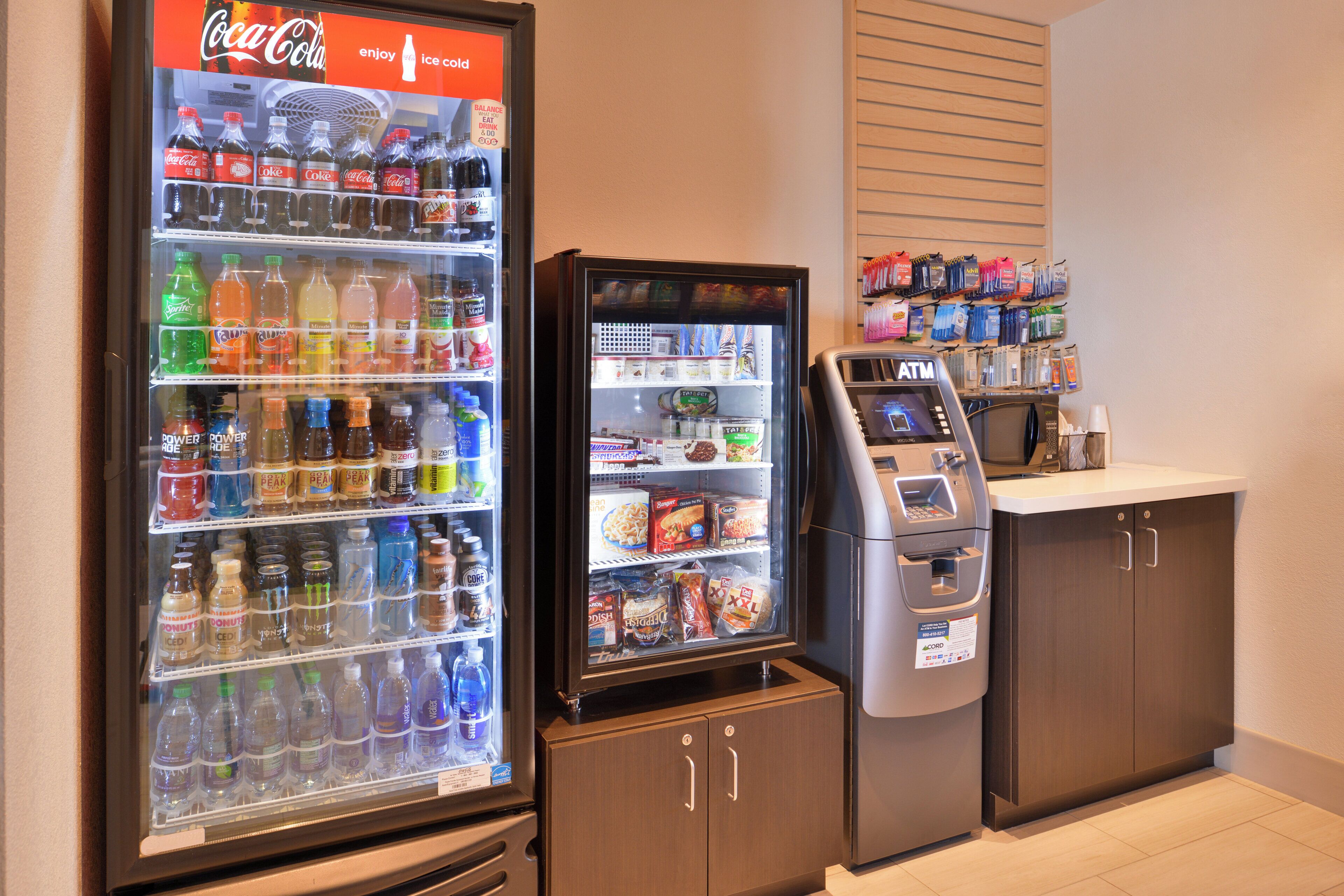 Un espace équipé d’un distributeur automatique, d’un réfrigérateur à boissons Coca-Cola et d’un four à micro-ondes.