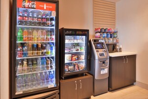 A vending machine area with a Coca-Cola cooler and a microwave.