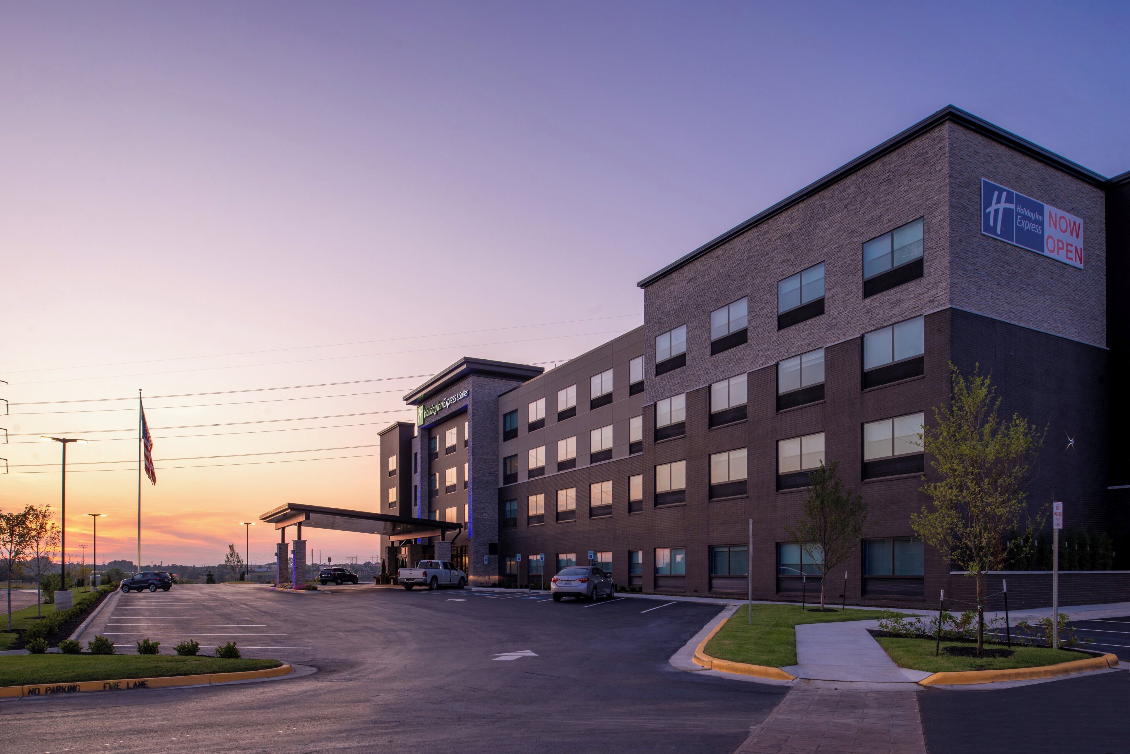 Edificio Holiday Inn Express con fachada de ladrillo, múltiples ventanales y estacionamiento.