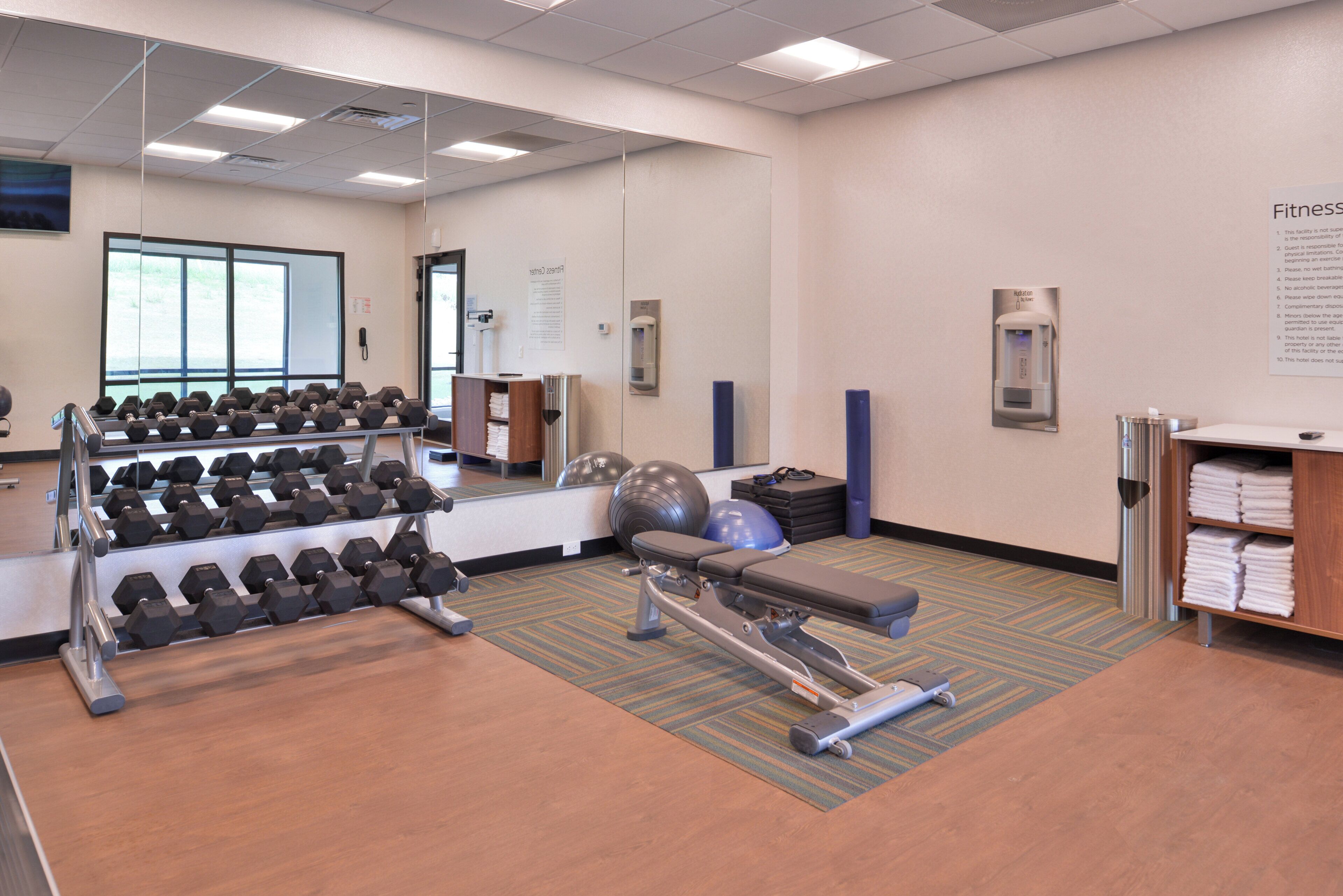 Ein Fitnessstudio mit Hanteln, Übungsbällen und einem Ergometer.