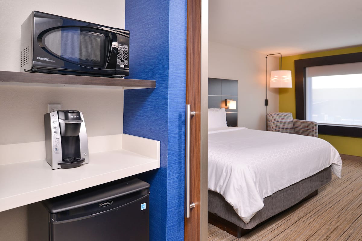 A hotel room with a microwave, coffee maker, and a bed.