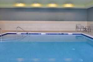 A swimming pool with a metal ladder, tiled walls, and a few chairs. - Holiday Inn Express & Suites Olathe West by IHG (Olathe)