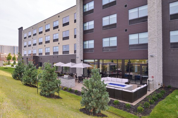 A multi-story hotel with outdoor seating and a pool area. - Holiday Inn Express & Suites Olathe West by IHG (Olathe)