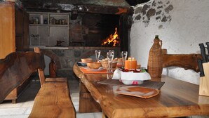 A rustic dining area with a wooden table, benches, and a brick fireplace. - House Sandra (Stokici)