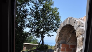 A window view of a stone structure with a brick wall and a wooden bench. - House Sandra (Stokici)