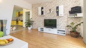 Una sala de estar moderna con televisor de pantalla plana, mueble blanco para entretenimiento y pared con diseño de ladrillo.